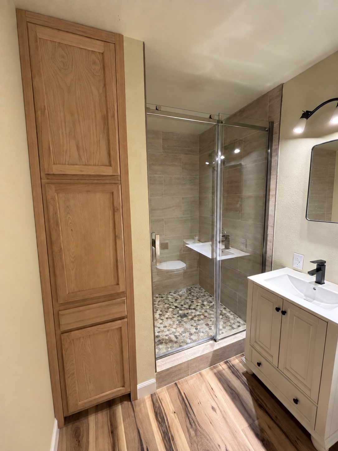 Finished bathroom remodel with glass walk-in shower, new vanity and wood-look flooring
